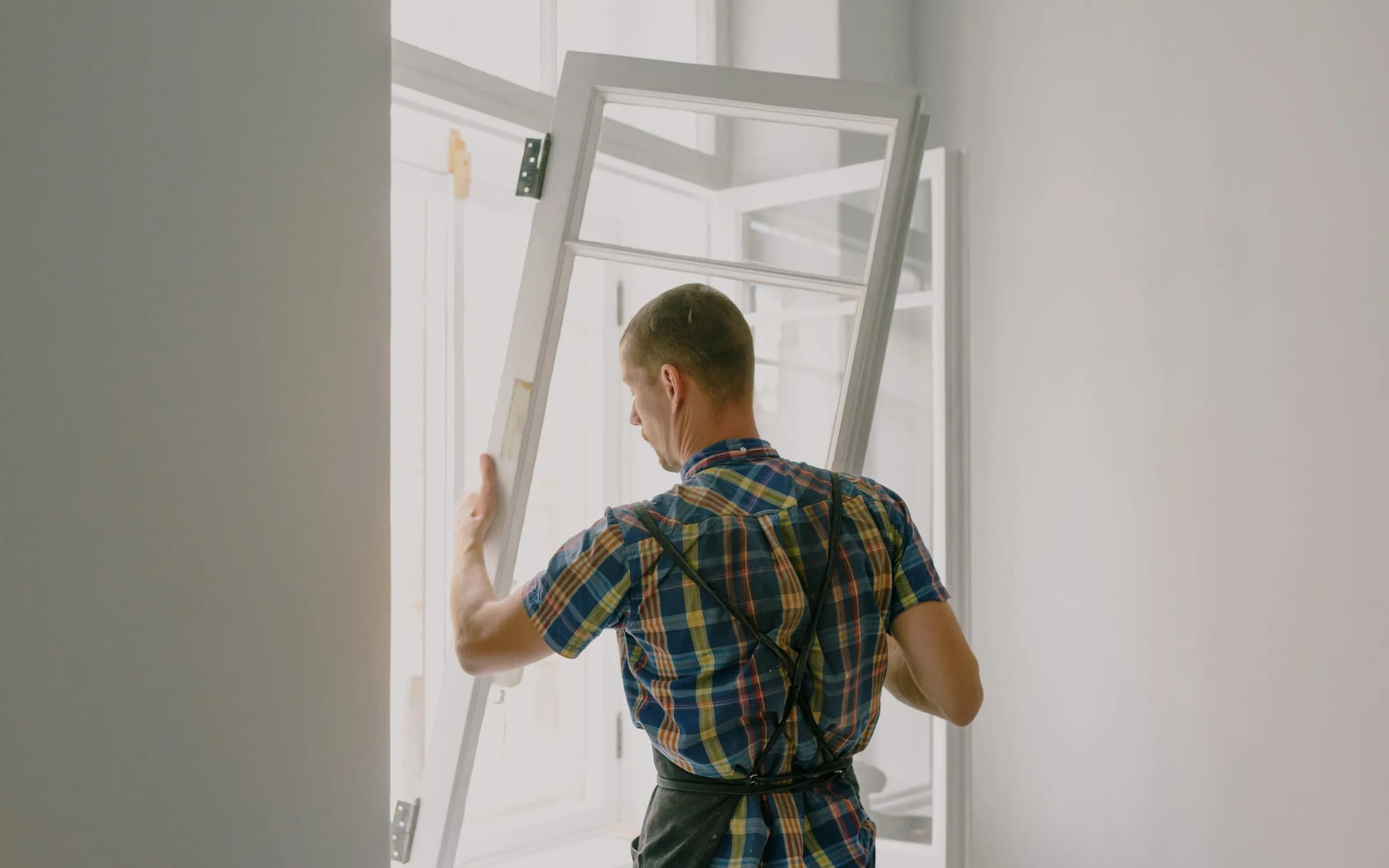 Beyaz PVC pencere kasasını açıklığa yerleştiren uygulamacı