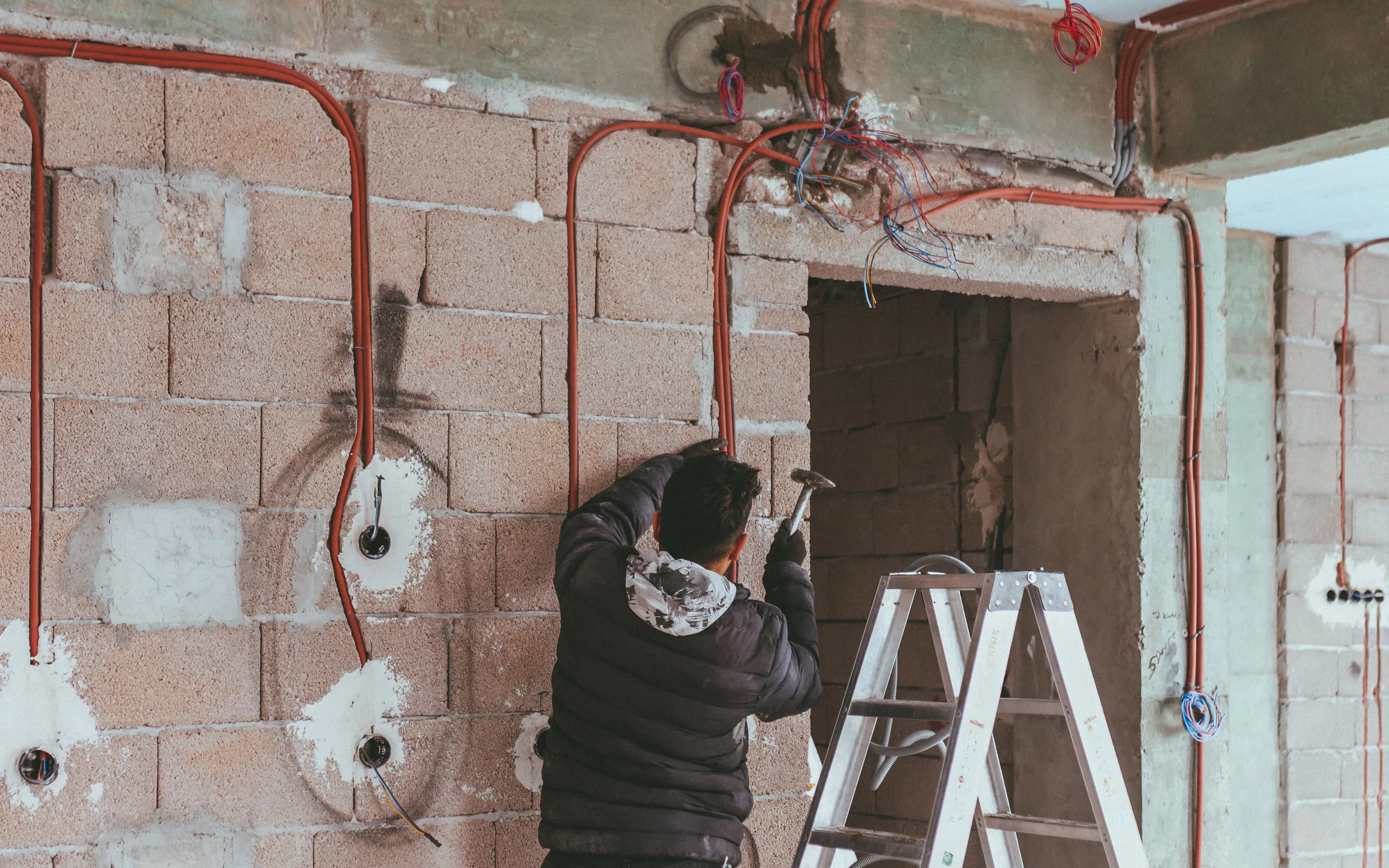 Konut yenileme alanında duvar içi elektrik hattı üzerinde çalışan usta